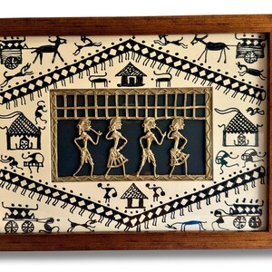 May include: A framed artwork featuring a black and white drawing of a village scene with a central panel depicting four figures in gold metalwork. The figures are playing musical instruments and are set against a dark blue background.