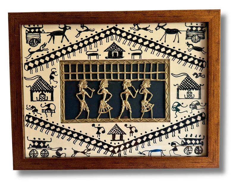 May include: A framed artwork featuring a black and white drawing of a village scene with a central panel depicting four figures in gold metalwork. The figures are playing musical instruments and are set against a dark blue background.