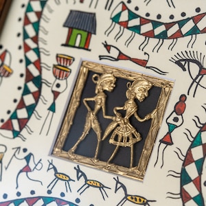 May include: A framed artwork with a white background and black lines depicting various figures and animals. A small gold-colored frame with a black background contains a raised image of two figures in a dancing pose.