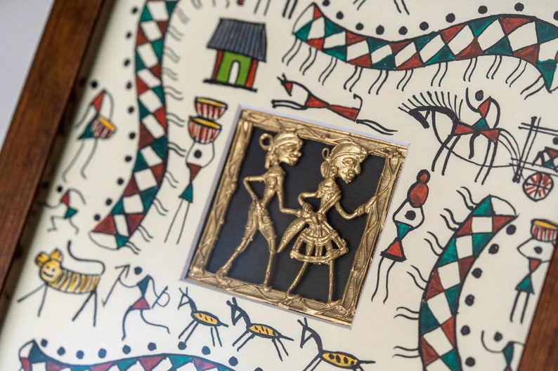 May include: A framed artwork with a white background and black lines depicting various figures and animals. A small gold-colored frame with a black background contains a raised image of two figures in a dancing pose.