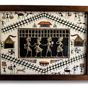 May include: A framed artwork featuring a traditional Indian folk art style with a white background and black and green geometric patterns. The centre of the artwork features a metal cutout of four figures in a dance pose, set against a black background.