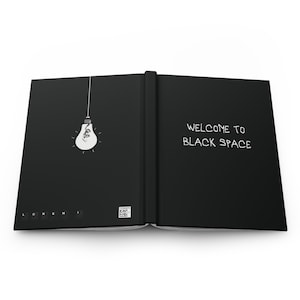 Puede incluir: Cuaderno negro abierto con el texto "WELCOME TO BLACK SPACE" en la página derecha y un dibujo de una bombilla en la página izquierda.