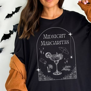 May include: Black t-shirt with a white graphic design of a margarita with the text "Midnight Margaritas" above it.