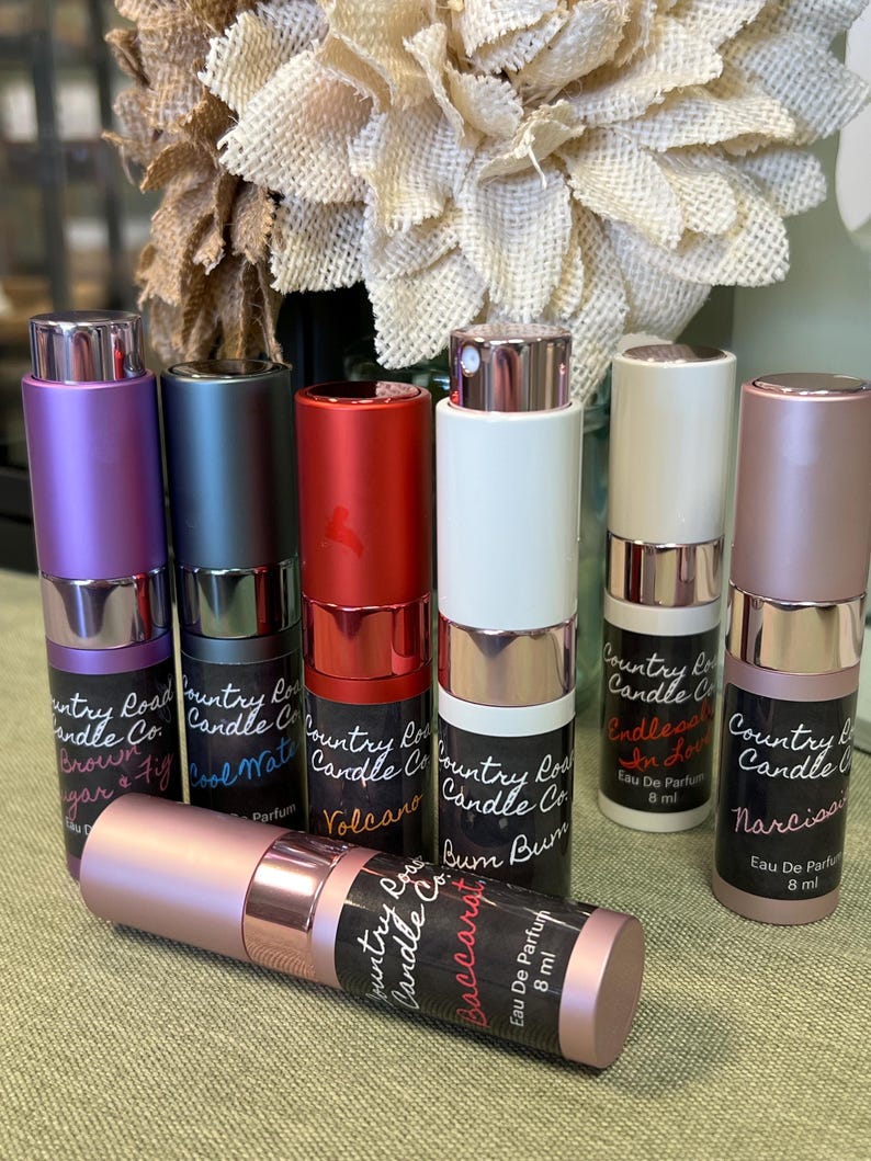Puede incluir: Ocho peque&ntilde;os frascos de perfume con tapas doradas y etiquetas que dicen "Country Road Candle Co." y diferentes aromas, incluyendo "Brown Sugar & Fig", "Cool Water", "Volcano", "Bum Bum", "Endless In Love" y "Narciso".