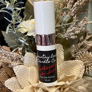 Puede incluir: Botella blanca con una etiqueta en blanco y negro que dice "Country Road Candle Co. Endlessly In Love Eau De Parfum 8 ml".