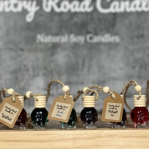 May include: A row of eight glass skull-shaped car air fresheners with wooden tops and string hangers. Each air freshener has a different scent label: Leather, Fresh Linen, Midnight Ice, and Cherry.