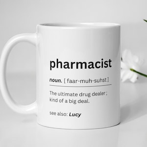 May include: White ceramic mug with a black design that says "pharmacist" and defines the word as "The ultimate drug dealer; kind of a big deal."  The mug also says "see also: Lucy".