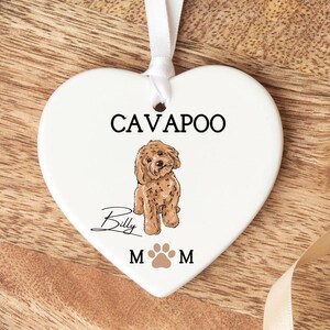 May include: White ceramic heart ornament featuring a brown Cavapoo dog illustration, the name "Billy" written in cursive, and the text "Cavapoo" and "Mom" on either side of a paw print.