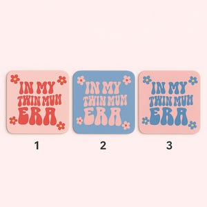 Puede incluir: Tres posavasos cuadrados con el texto "IN MY TWIN MUM ERA" en una fuente retro. Los posavasos son rosas, azules y rosas, con detalles florales. Los n&uacute;meros 1, 2 y 3 est&aacute;n debajo.