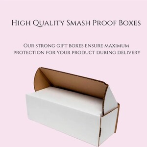 Puede incluir: Una caja rectangular blanca con interior marr&oacute;n, abierta para revelar un interior blanco. El texto "HIGH QUALITY SMASH PROOF BOXES" est&aacute; en la parte superior, con texto adicional debajo que dice "OUR STRONG GIFT BOXES ENSURE MAXIMUM PROTECTION FOR YOUR PRODUCT DURING DELIVERY."