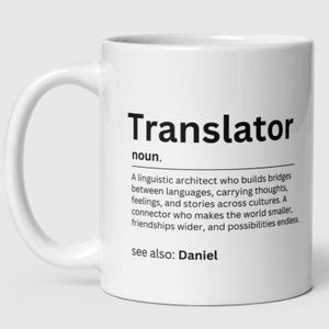 May include: White ceramic mug featuring the word "Translator" in black, with a definition below. The mug also includes the text "See also: Daniel". The mug has a curved handle, suitable for hot beverages.