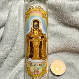 May include: A white candle with a gold and rainbow label featuring a skeletal figure in a golden robe. The label reads "Run Devil Run" with a pentagram symbol below.