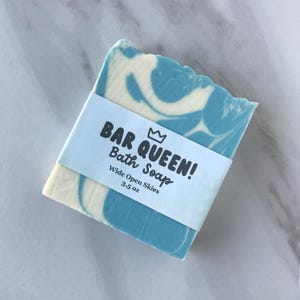 Op de afbeelding: Een blauwe en witte gemarmerde zeep met een label waarop "Bar Queen! Bath Soap" en "Wide Open Skies 3.5 oz" staat.