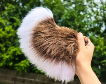 May include: A fluffy faux fur tail accessory featuring a gradient color pattern that transitions from white at the tip to a rich brown in the center and back to white at the base, attached to a small metal clip for secure fastening.
