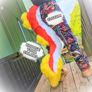 Può includere: Una lunga coda in pelliccia sintetica felpata con un vivace motivo tricolore rosso, giallo e bianco. La coda è attaccata a pantaloni cargo fantasia. Le sovrapposizioni di testo sull'immagine riportano CUSTOM e CHOOSE YOUR COLORS.