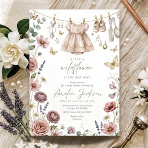 May include: Baby shower invitation with a watercolor floral design. The invitation features a pink dress, baby shoes, and butterflies hanging on a clothesline. Text reads "A Little Wildflower Is On Her Way" and details for Amelia Jackson's shower.