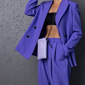 Minimalist and small crossbody phone case in purple paired with a deep blue outfit of a blazer and pleated pants. Elevate your style with stylish quality pieces