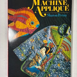 May include: A book titled Machine Appliqué by Sharon Perna with a black cover. The cover features a colourful fabric fish and a blue quilted jacket with a floral pattern and an appliqué of a person in traditional attire with a fan design.