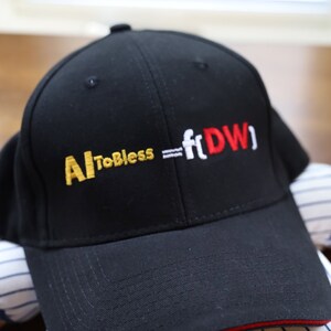Puede incluir: Gorra de béisbol negra con un logotipo bordado en rojo y blanco que dice "AI To Bless = ft(DW)" en amarillo.