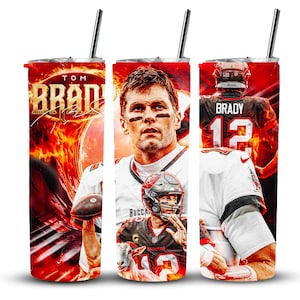 Puede incluir: Un vaso rojo, blanco y negro con una foto de Tom Brady. El vaso tiene una pajita y el texto "TOM BRADY" en él.