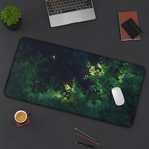 Puede incluir: Alfombrilla de escritorio rectangular con una escena de bosque bajo un cielo estrellado y una luna creciente. La alfombrilla tiene un borde negro y un ratón de ordenador blanco está en el lado derecho. También se ven un portátil, una taza de café y artículos de papelería.