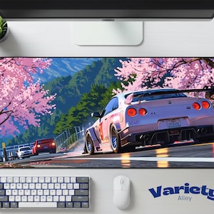May include: A large rectangular mouse pad featuring a stylized image of a white sports car racing on a track lined with cherry blossom trees. The background includes mountains and a blue sky. The text "Variety Alley" is in the lower right corner.