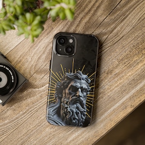May include: Black phone case with a gold and black design featuring a sculpted bust of a man with a beard and a halo of light rays.