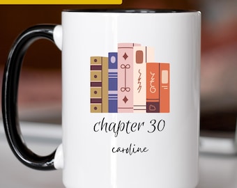 May include: A white ceramic mug with a black handle and interior. The front features a graphic of colorful book spines above the black text "chapter 30" and the name "caroline" in a cursive font. A yellow banner at the top reads "PERSONALIZED GIFT!"