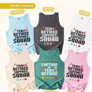 May include: Six sleeveless tank tops in light blue, black, white, ivory, light green, and pink. Five feature the text "TEAM RETIREE SUPPORT SQUAD" with pixelated ghosts and party icons. One green tank features "CAPTAIN OF TEAM RETIREE" with beer mugs.