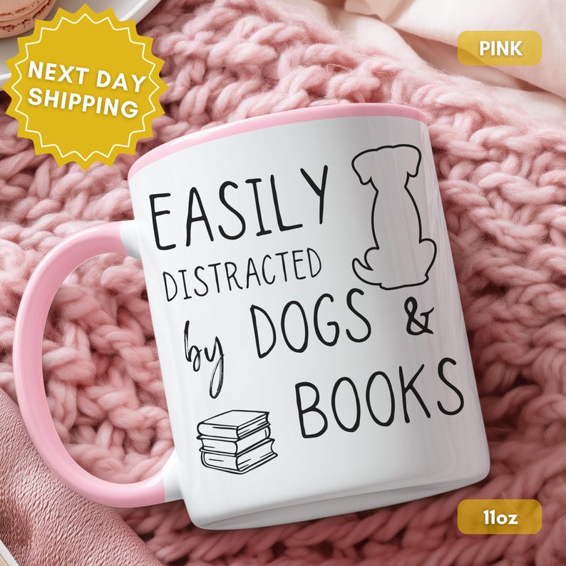 White ceramic mug with a black handle and rim. The mug features the text "EASILY DISTRACTED by DOGS & BOOKS" in black, along with a dog silhouette and stacked books.