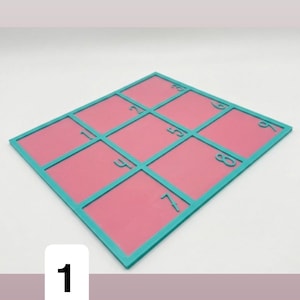 Pode incluir: Um quebra-cabeça quadrado de duas cores com uma moldura turquesa e quadrados internos rosa. O quebra-cabeça é dividido em nove seções, cada uma com um número de 1 a 9. O número 1 está em um quadrado branco no canto inferior esquerdo.