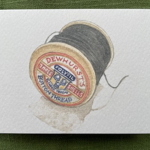 May include: A spool of black thread with a white label that reads "DEWHURST'S POLYFILL SHELLS THREE BUTTON THREAD".