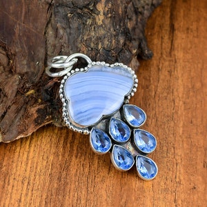 Könnte beinhalten: Ein silberner Anhänger mit einer blauen Achatwolke, einer silbernen Kette und blauen Edelstein-Regentröpfchen, die unten hängen.
