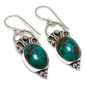 May include: A pair of silver earrings with green and brown gemstone drops. The earrings have a delicate, ornate design with a floral motif.