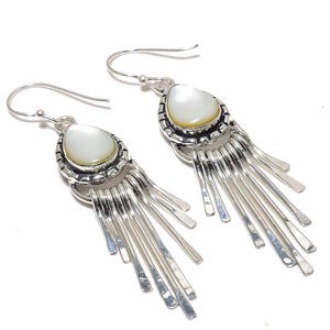 May include: Silver dangle earrings with a white mother of pearl teardrop shaped stone and a fringe of silver strands.