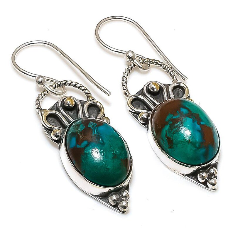 May include: A pair of silver earrings with green and brown gemstone drops. The earrings have a delicate, ornate design with a floral motif.