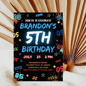 May include: A black and white birthday invitation with colorful accents. The invitation is for Brandon's 5th birthday party. It includes the date, time, and location of the party. The text "JOIN US TO CELEBRATE" is at the top of the invitation.