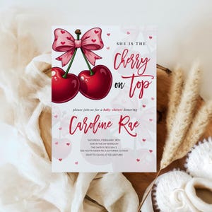 May include: Baby shower invitation with a pair of red cherries and a pink bow. The text says "She is the Cherry on Top" and invites guests to celebrate Caroline Rae. Includes date, time, and location details in a decorative font.