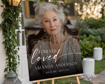 May include: A memorial sign on an easel features a portrait of a woman with the words "Forever Loved" in elegant script. The sign includes the name "Amanda Anderson" and dates "Apr 25, 1945 - Sept 5, 2025".