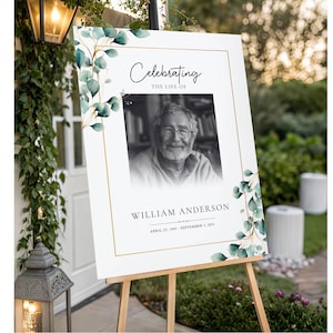 May include: A rectangular memorial sign featuring a black and white portrait of a man, the text Celebrating THE LIFE OF, WILLIAM ANDERSON, and the dates APRIL 25, 1945 - SEPTEMBER 5, 2025, framed by a gold border and watercolor eucalyptus leaves.