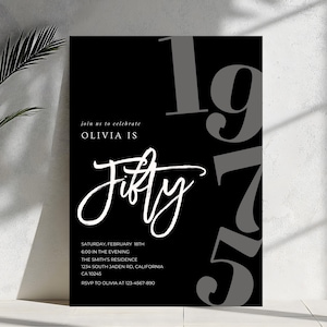 May include: A black and white invitation for Olivia's 50th birthday. The design features the word "Fifty" in elegant script, with the year "1975" in large gray numbers. Additional text includes event details: date, time, location, and RSVP information.