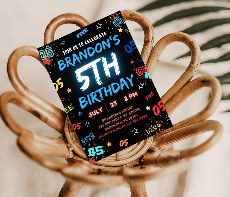 May include: A black and white birthday invitation with colorful accents. The invitation says "Join us to celebrate Brandon's 5th Birthday" with a neon blue "5th" and a date of July 23rd at 2 PM. The invitation also includes the address and RSVP information.