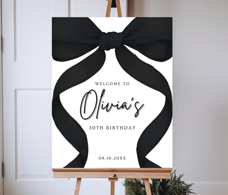 May include: A white welcome sign with a black bow on top. The sign reads "Welcome to Olivia's 30th Birthday 08.16.20XX".