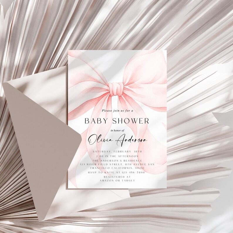 May include: A baby shower invitation featuring a watercolor pink bow design. The invitation includes the text "Baby Shower" and details for Olivia Anderson's shower, including the date, time, and location. An envelope is partially visible in the background.