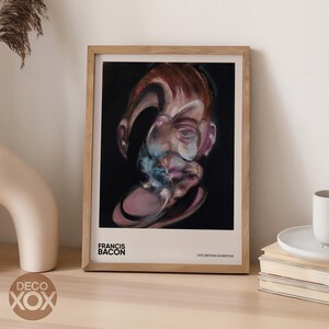 May include: Framed art print featuring a Francis Bacon painting. The artwork depicts a distorted portrait with a dark background. The frame is made of light-colored wood. Text at the bottom reads "FRANCIS BACON" and "TATE BRITAIN EXHIBITION."