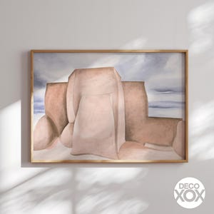 May include: A framed abstract art print featuring a watercolor painting in shades of beige, brown, and blue. The artwork depicts a stylized landscape with soft, rounded forms, set against a cloudy sky. The print is encased in a light brown wooden frame.