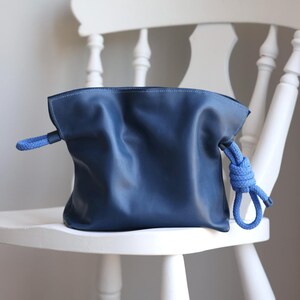 May include: A dark blue leather bag with a knotted blue rope handle.