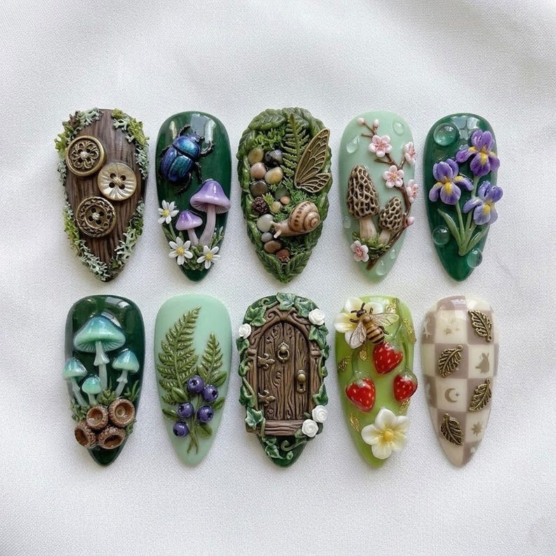 May include: A collection of ten intricately designed nail art pieces. Each nail features a unique, nature-inspired design, including mushrooms, beetles, flowers, and a miniature fairy door. The color palette includes greens, browns, and pastels, with detailed textures.