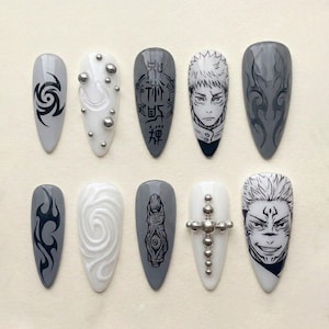 May include: A set of ten long, almond-shaped artificial nails. Designs include tribal patterns, silver studs, and anime-style character faces. The color palette is primarily gray, white, and black, with a glossy finish.