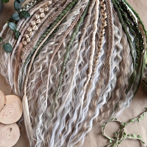 Könnte beinhalten: Ein Set synthetischer Haarverlängerungen in den Farben Weiß, Blond und Grün. Die Verlängerungen sind geflochten und wellig, einige Strähnen haben Perlen.